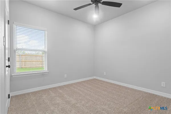 an empty room with a window and a fan