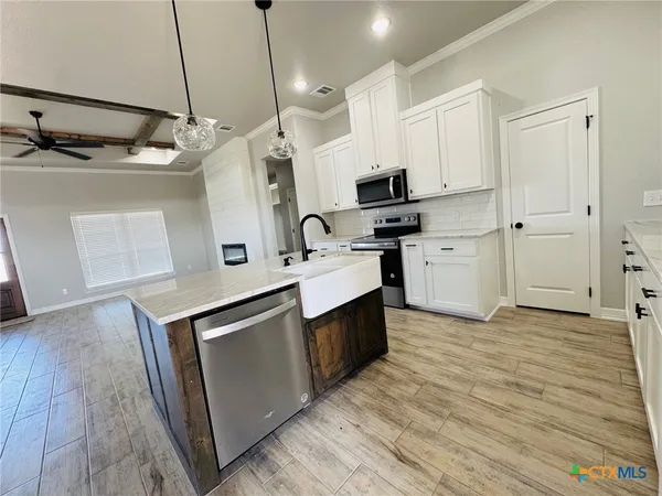 a kitchen with stainless steel appliances granite countertop a sink a stove and a wooden floors