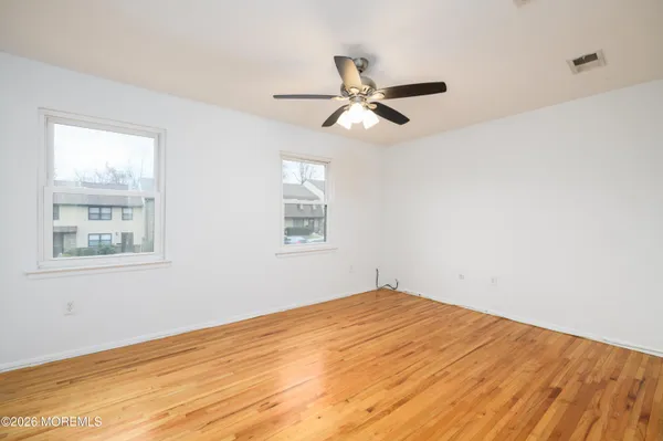a view of empty room with wooden floor and fan