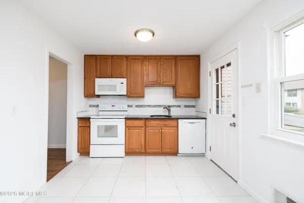 a kitchen with granite countertop a sink cabinets stainless steel appliances and a window