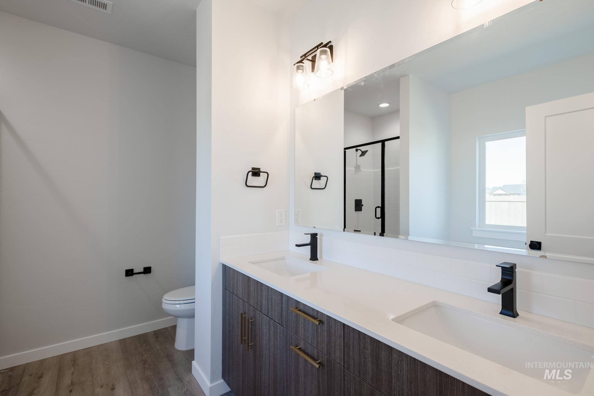 2231 South Border Way Meridian, ID 83642 - Photo 20 of 23 Bathroom with double vanity, a shower stall, and dark wood finished floors