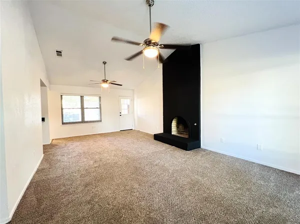 an empty room with windows and fan
