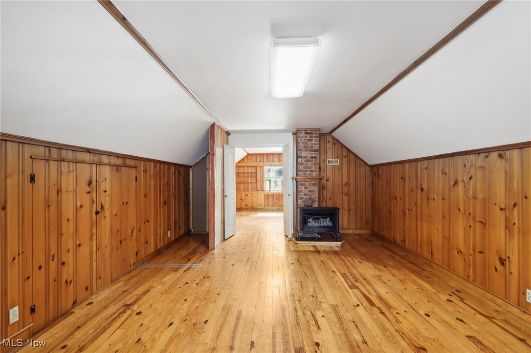 1042 Renfield Road Cleveland Heights, OH 44121 - Photo 30 of 49 Additional living space with light wood-type flooring, wood walls, vaulted ceiling, and a wood stove