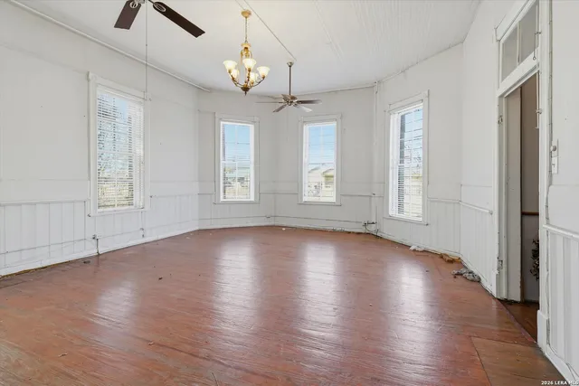 a view of an empty room with wooden floor fireplace and a window