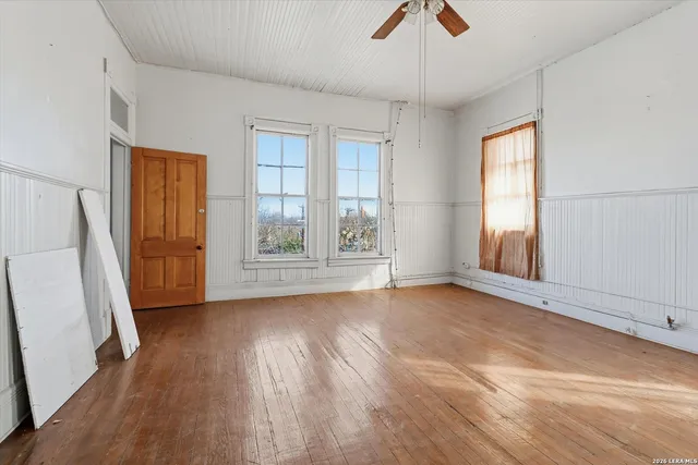 a view of an empty room with wooden floor and a window