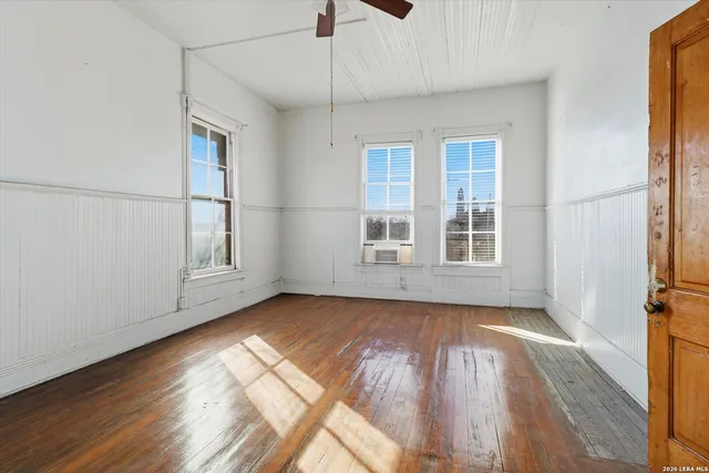 an empty room with wooden floor and windows