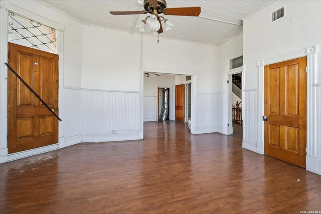 an empty room with wooden floor fireplace and windows