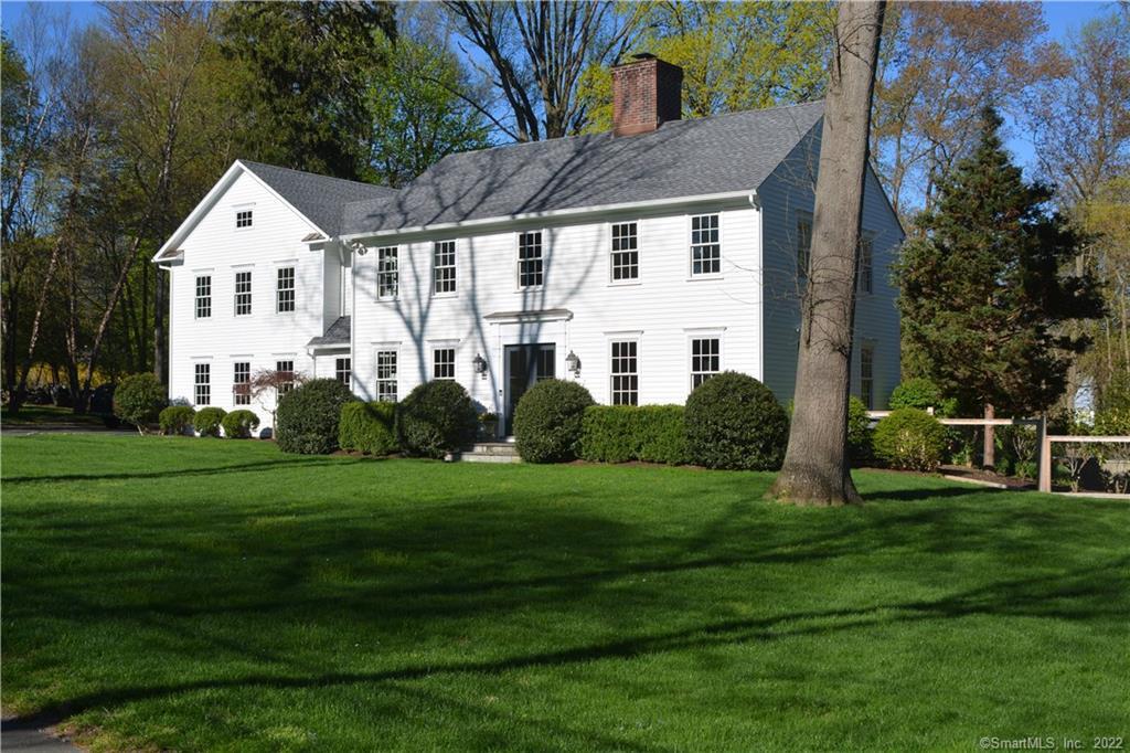 a view of a white house with a yard and trees