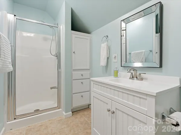 a spacious bedroom with a bed a mirror and lamp