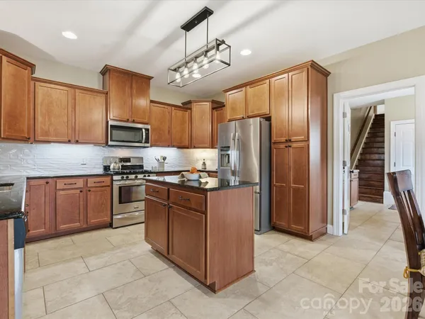 a kitchen with stainless steel appliances granite countertop a refrigerator and a stove top oven