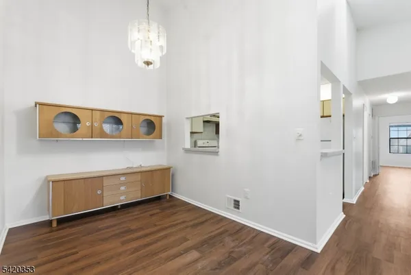 a view of a hallway with wooden floor and chandelier