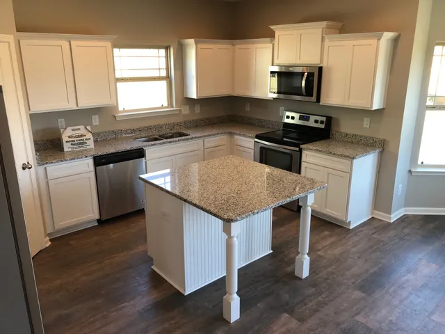 a kitchen with stainless steel appliances granite countertop a sink stove microwave and refrigerator