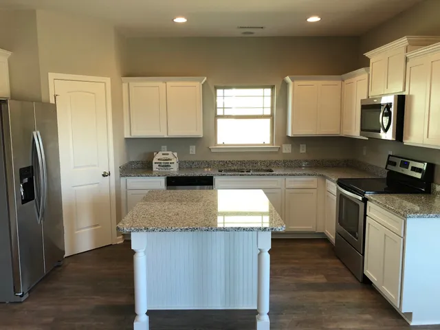 a kitchen with stainless steel appliances granite countertop a refrigerator a stove a sink dishwasher and microwave with wooden floor