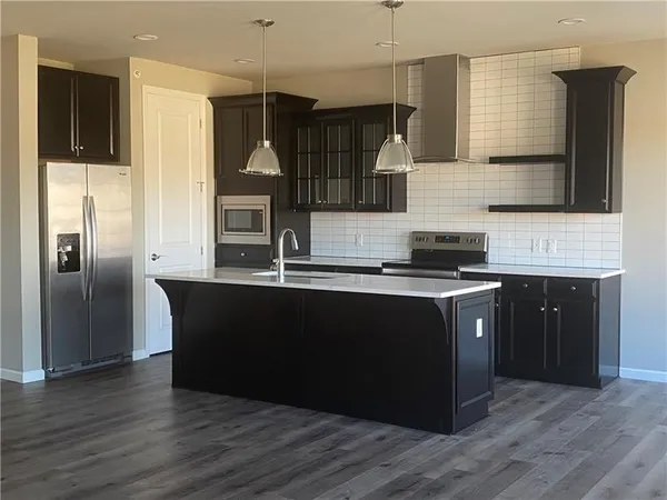 a kitchen with granite countertop a refrigerator and a stove top oven