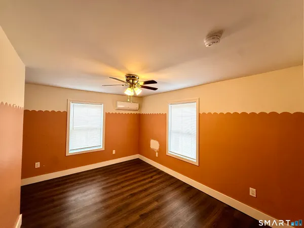 a view of an empty room with a window and wooden floor