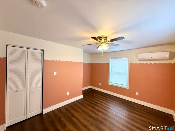 a view of an empty room with window and wooden floor