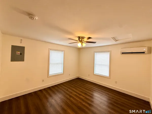 a view of empty room with wooden floor and fan