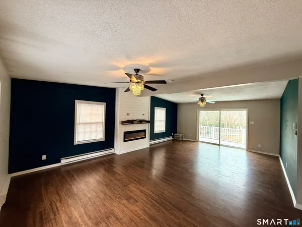 a view of an empty room with a window and wooden floor