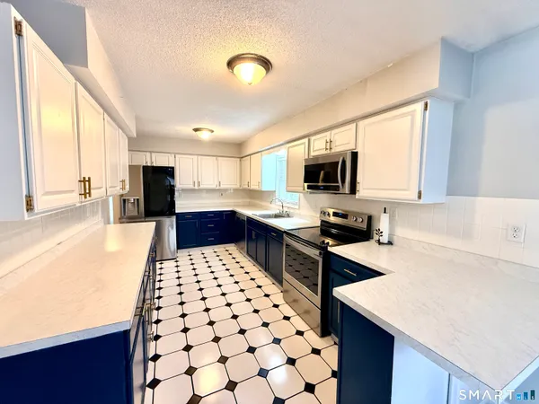 a kitchen with stainless steel appliances kitchen island granite countertop a sink stove and refrigerator