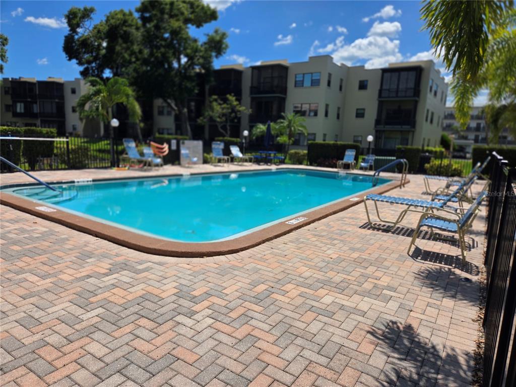 5925 Terrace Park Drive North, Unit 106 St. Petersburg, FL 33709 - Photo 21 of 22 a view of swimming pool with outdoor seating and yard in front of it