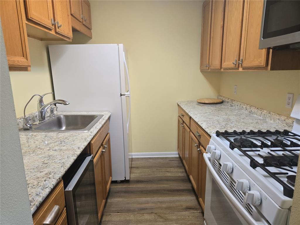 5925 Terrace Park Drive North, Unit 106 St. Petersburg, FL 33709 - Photo 10 of 22 a kitchen with granite countertop a sink stove and cabinets