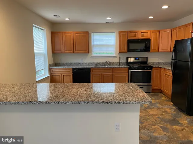 a kitchen with granite countertop stainless steel appliances and wooden cabinets