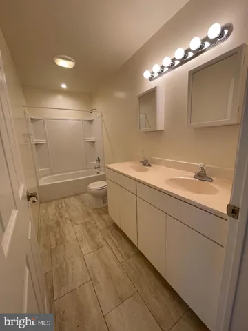 a bathroom with a sink a toilet a mirror and shower