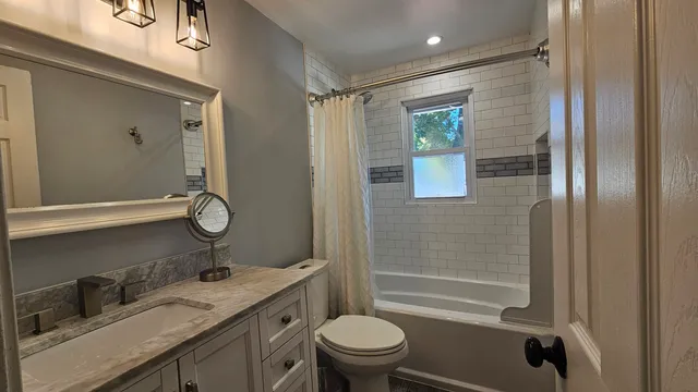 a bathroom with a granite countertop sink toilet and shower