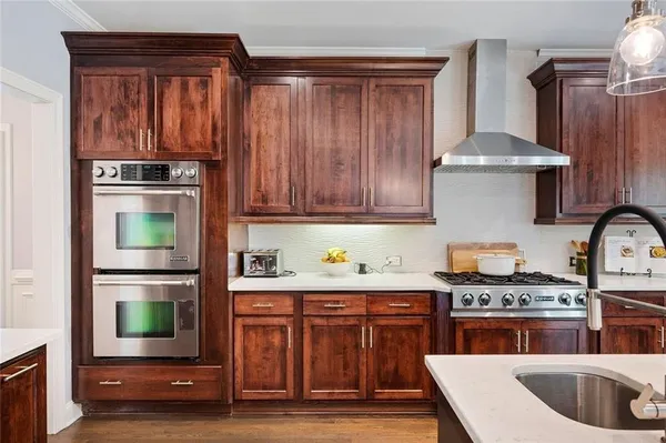 a kitchen with a sink stove and wooden floor