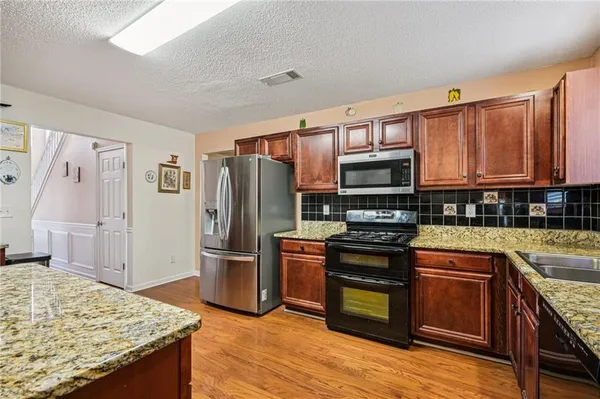 a kitchen with stainless steel appliances granite countertop a refrigerator stove and sink