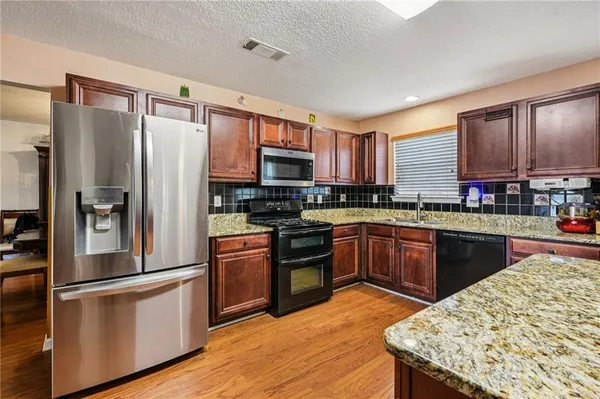 a kitchen with stainless steel appliances granite countertop a refrigerator a stove and a sink