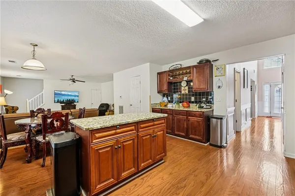a kitchen with stainless steel appliances kitchen island granite countertop wooden floors and wooden cabinets