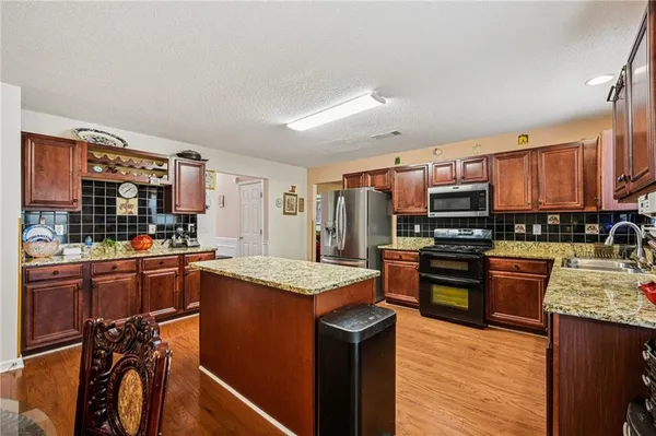 a kitchen with stainless steel appliances kitchen island granite countertop a stove refrigerator and sink