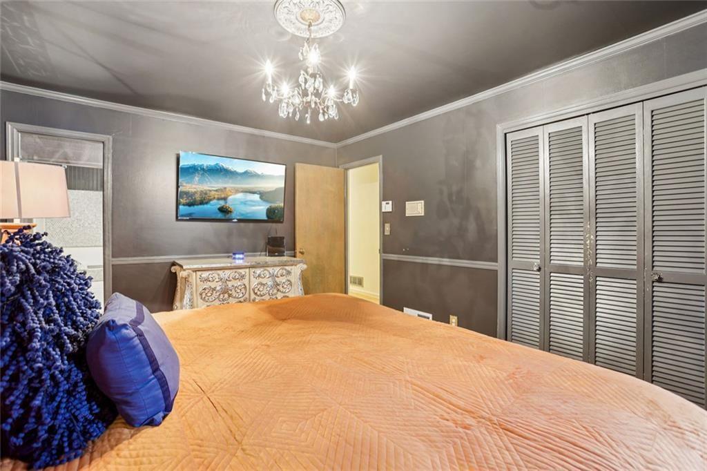6300 East Stubbs Road Atlanta, GA 30349 - Photo 17 of 29 a bedroom with a large bed and a chandelier