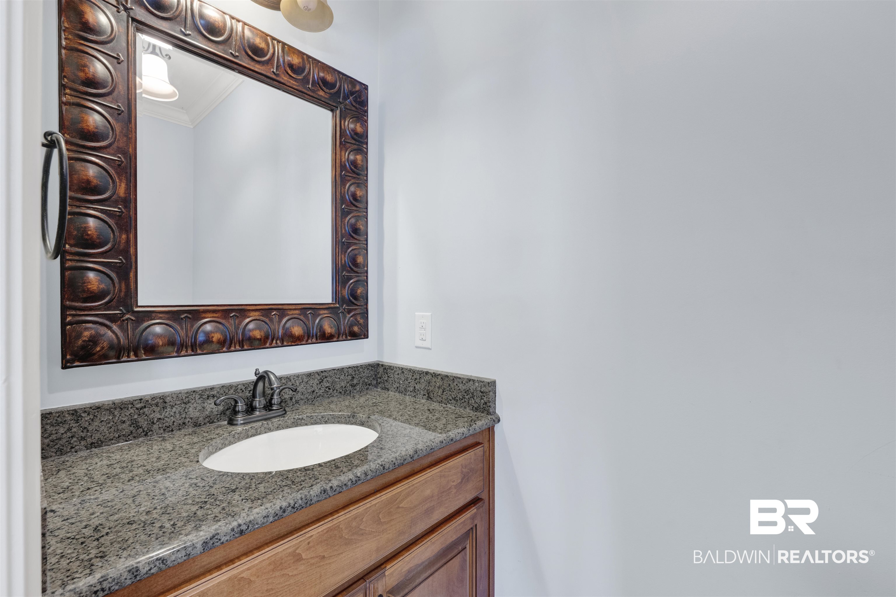 12944 Anna's Way Stapleton, AL 36578 - Photo 63 of 64 Bathroom vanity featuring a decorative framed mirror, granite countertop, undermount sink, and wood-finish cabinetry