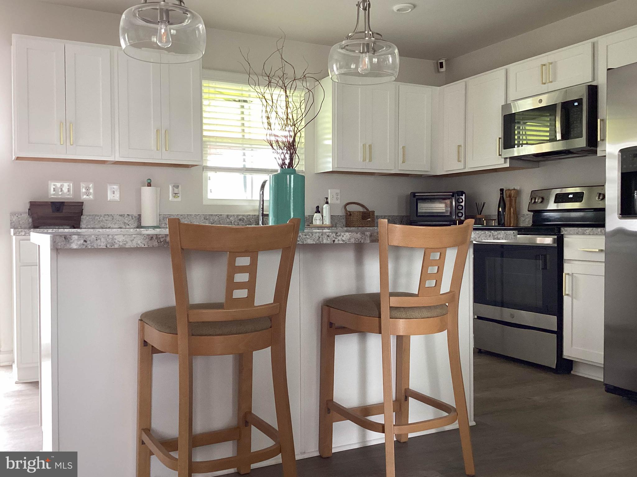 212 Bowline Drive Cambridge, MD 21613 - Photo 5 of 19 a kitchen with stainless steel appliances granite countertop a stove a sink dishwasher a dining table and chairs with wooden floor