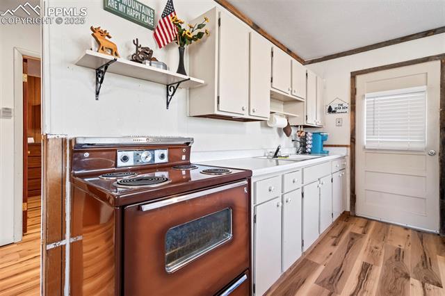 616 Timber Ridge Road Divide, CO 80814 - Photo 9 of 34 Kitchen with electric range oven, open shelves, a sink, light wood-style floors, and white cabinetry