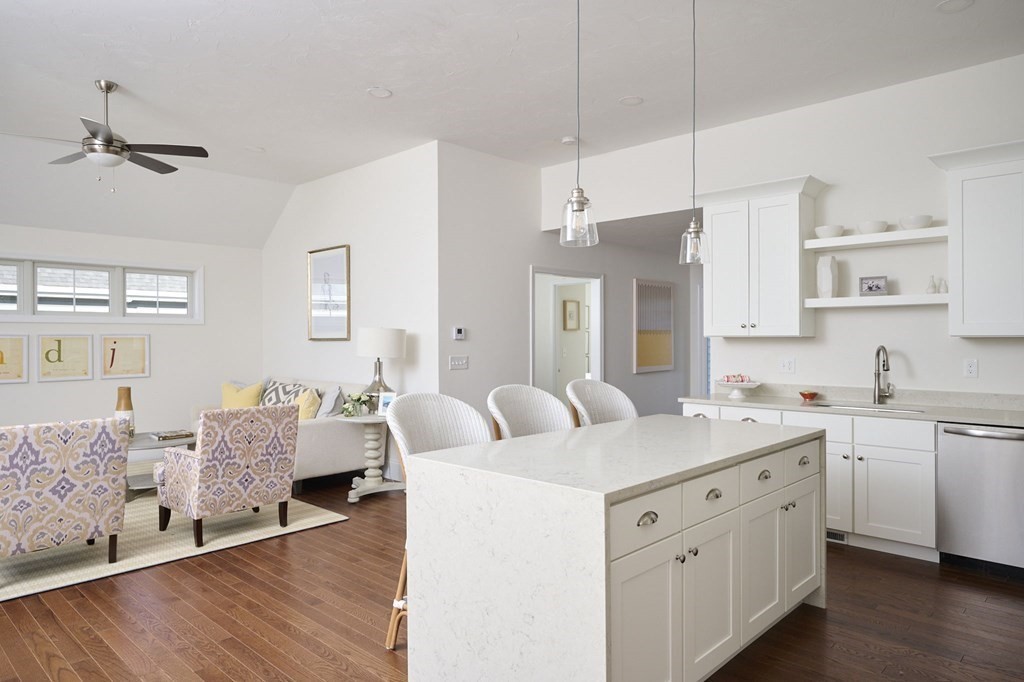 a spacious kitchen with a wooden floor and white cabinets