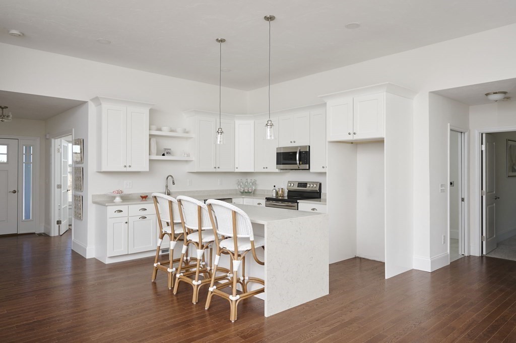 35 Metacomet Road, Unit 35 West Bridgewater, MA 02379 - Photo 5 of 34 a kitchen with stainless steel appliances granite countertop a refrigerator a stove top oven a island with wooden floor and cabinets