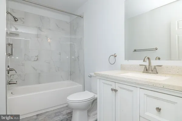 a bathroom with a granite countertop sink a toilet and bathtub