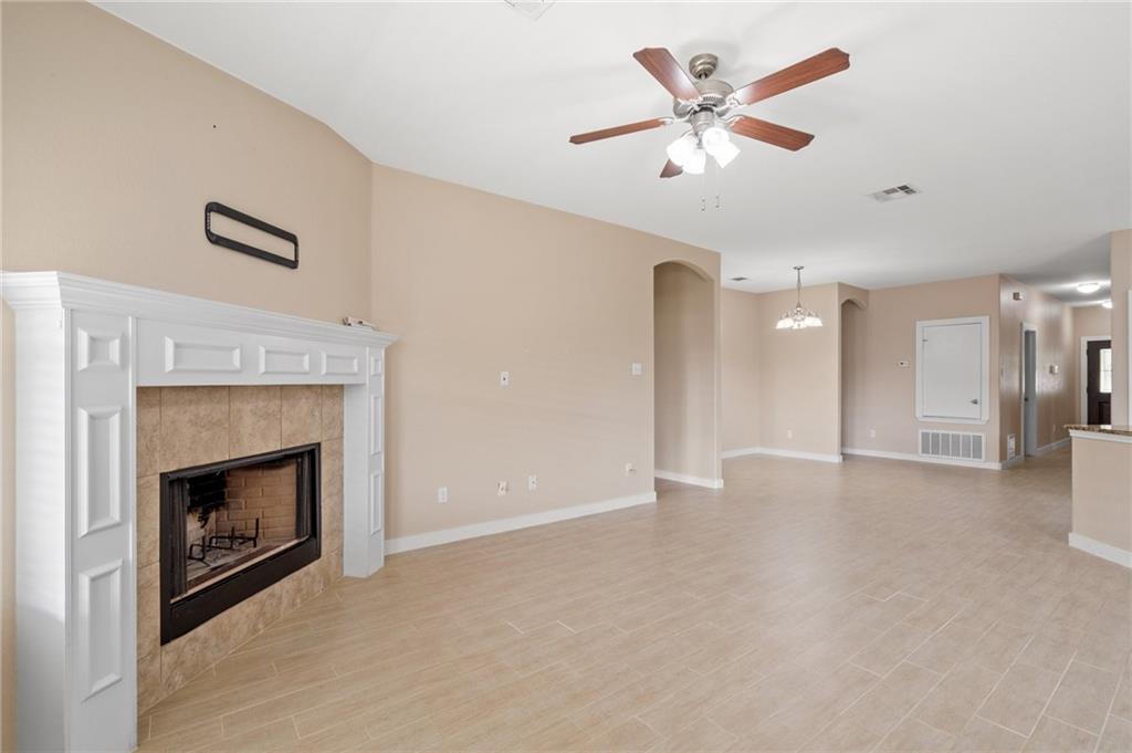 20224 Merlin Falcon Trail Pflugerville, TX 78660 - Photo 12 of 40 A well-lit living area features an elegant corner fireplace and durable tile flooring throughout.