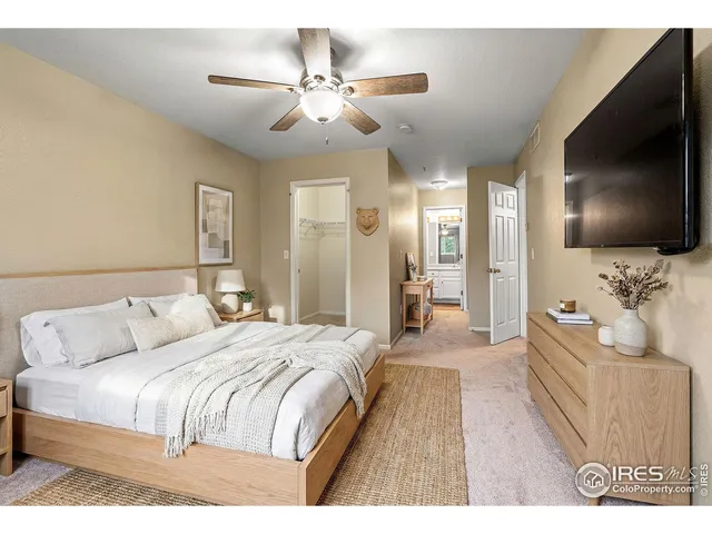 a spacious bedroom with a large bed a flat screen tv and a chandelier