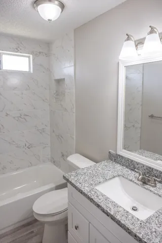 a bathroom with a granite countertop sink toilet and shower
