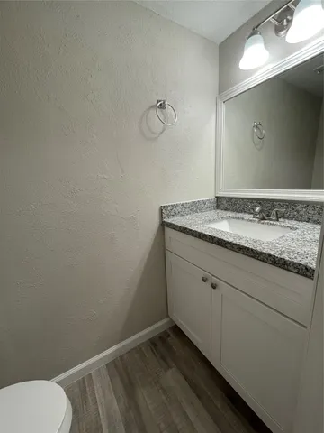 a bathroom with a granite countertop sink and a toilet