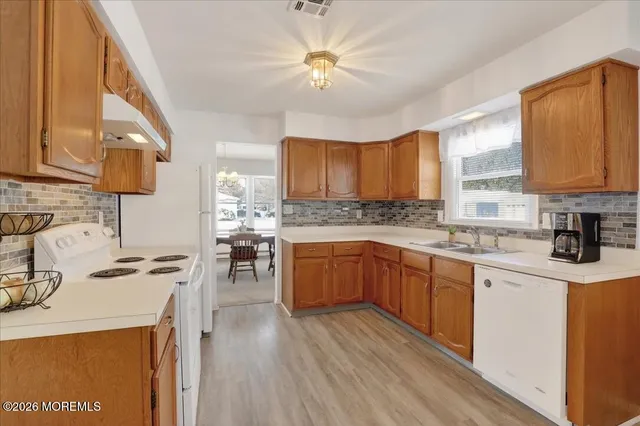 a kitchen with stove a sink dishwasher and a refrigerator with wooden floor
