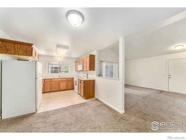 a open kitchen with cabinets and a refrigerator