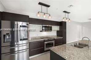 a kitchen with stainless steel appliances granite countertop a refrigerator a stove and a sink with wooden floor