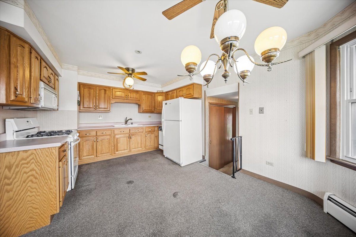 2316 185th Place Lansing, IL 60438 - Photo 8 of 21 a kitchen with a refrigerator a sink dishwasher a dining table and chairs with wooden floor