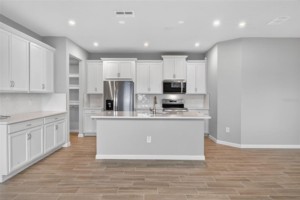 3350 Timber Xing Avenue Brandon, FL 33511 - Photo 5 of 35 a large kitchen with stainless steel appliances granite countertop a stove a sink a refrigerator and white cabinets with wooden floor