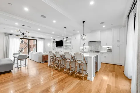a living room with stainless steel appliances furniture and a wooden floor